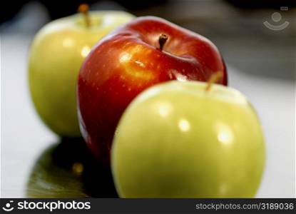 Close-up of two green apples and a red apple