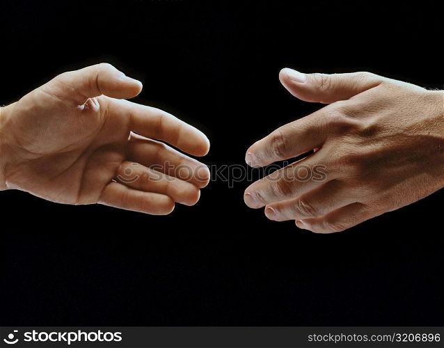 Close-up of two hands reaching towards each other