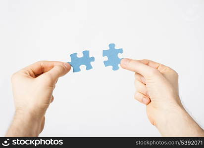 close up of two hands trying to connect puzzle pieces