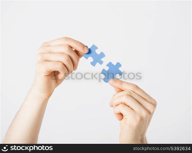 close up of two hands trying to connect puzzle pieces