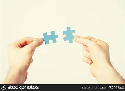 close up of two hands trying to connect puzzle pieces