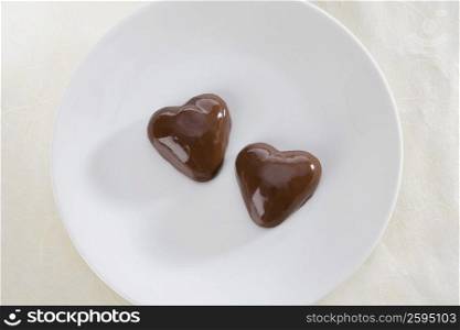 Close-up of two heart shaped chocolate candies in a plate