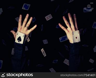 Close up of two human hands holding aces playing cards in the sleeve. Magician showing his trick on a black background with falling cards. Casino game win concept.