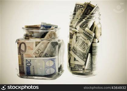 Close-up of two jars with Euros and dollar bills