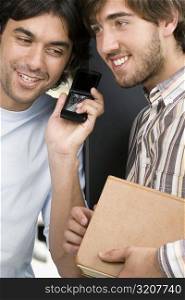 Close-up of two male university students listening to a mobile phone