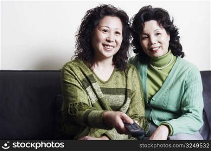 Close-up of two mature women sitting together on a couch smiling