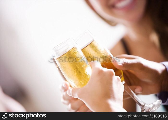 Close-up of two men and a woman toasting champagne flutes