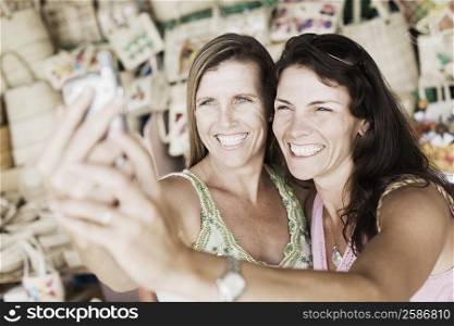 Close-up of two mid adult women holding a mobile phone and smiling
