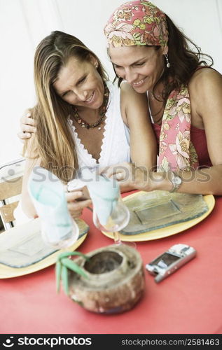 Close-up of two mid adult women looking at a digital camera and smiling