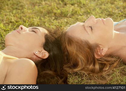 Close-up of two mid adult women lying on the grass with their eyes closed