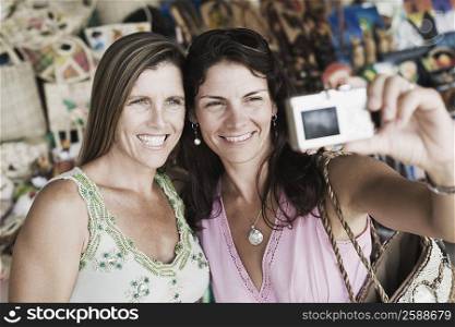 Close-up of two mid adult women taking a photograph of themselves