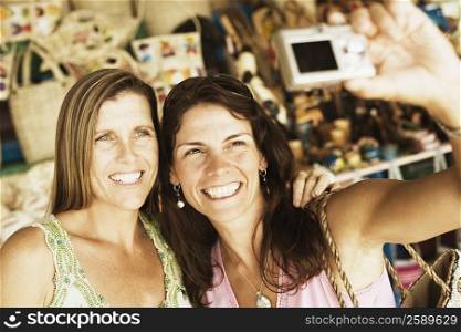 Close-up of two mid adult women taking a photograph of themselves