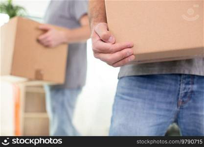close-up of two mover hand in uniform carrying cardboard box