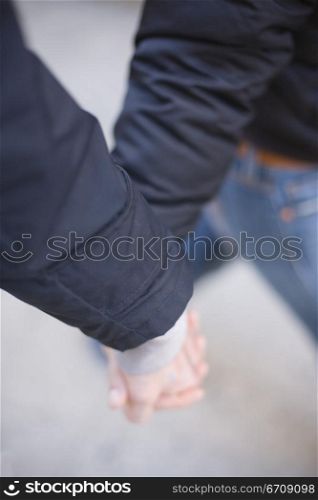 Close-up of two people holding hands and walking