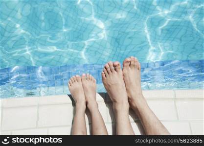 Close up of two people&rsquo;s legs by the pool side