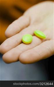 Close-up of two pills on a person&acute;s hand