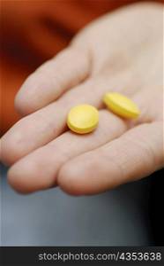 Close-up of two pills on a person&acute;s hand