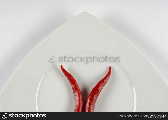 Close-up of two red chili peppers in a plate