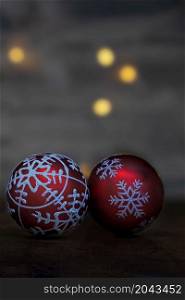 close up of two red glittering christmas baubles in front of a dark background