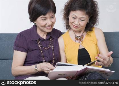 Close-up of two senior women looking at a photo album