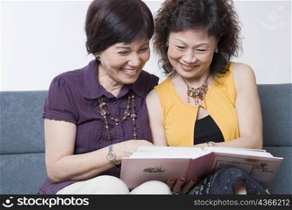 Close-up of two senior women looking at a photo album and smiling