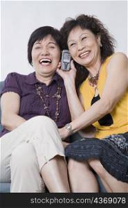 Close-up of two senior women talking on a mobile phone and smiling