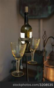 Close-up of two stem glasses with a wine bottle