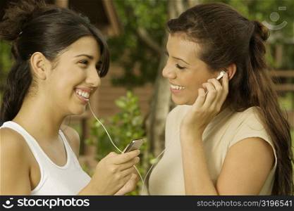Close-up of two teenage girls holding an MP3 player listening to music