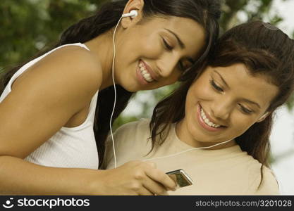 Close-up of two teenage girls holding an MP3 player listening to music