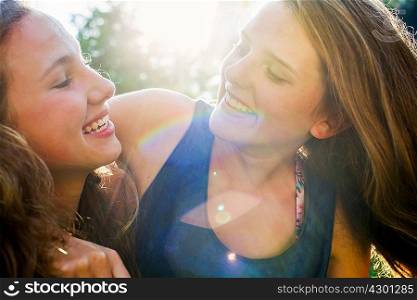 Close up of two teenage girls in sunlit park