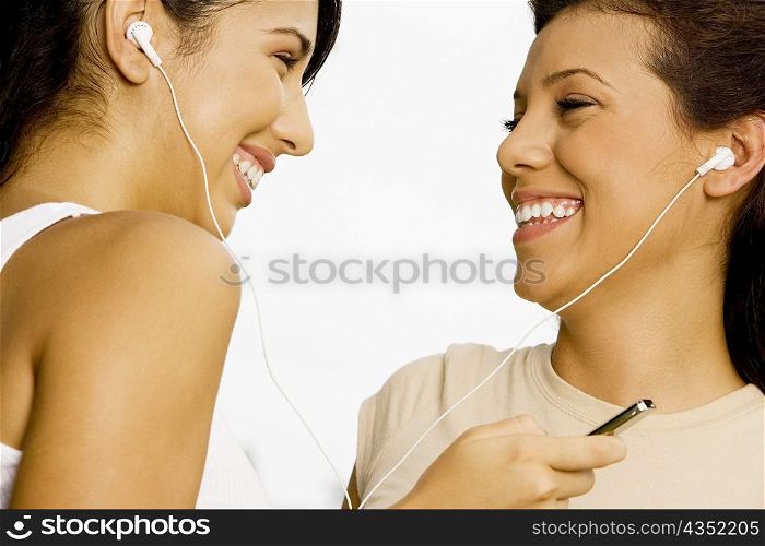 Close-up of two teenage girls listening to music with earphones