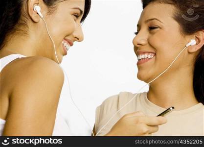 Close-up of two teenage girls listening to music with earphones
