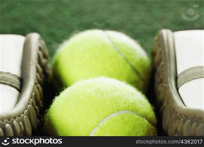Close-up of two tennis balls between tennis shoes