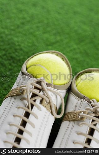 Close-up of two tennis balls in a pair of sports shoes
