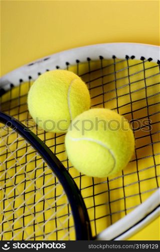 Close-up of two tennis balls on a tennis racket