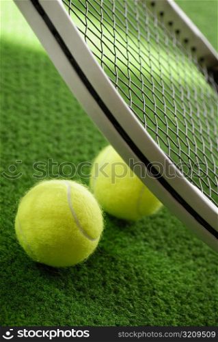 Close-up of two tennis balls with a tennis racket