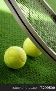 Close-up of two tennis balls with a tennis racket