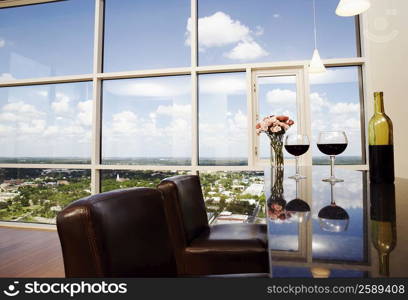 Close-up of two wine glasses with a wine bottle and a flower vase on the table