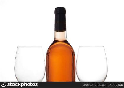 Close-up of two wineglasses with a wine bottle