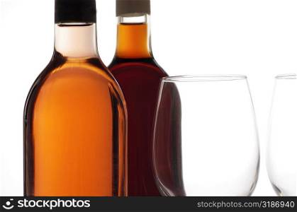 Close-up of two wineglasses with two wine bottles
