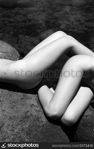 Close up of two young adult nude Caucasian women lying on boulders in Maui.