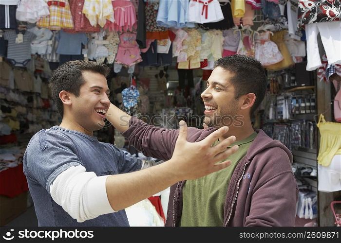 Close-up of two young men smiling in front of a clothing store