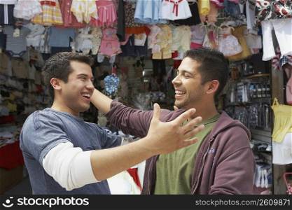 Close-up of two young men smiling in front of a clothing store