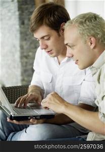 Close-up of two young men using a laptop