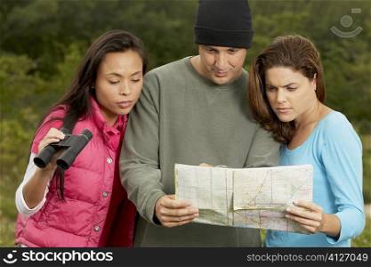 Close-up of two young women and a mature man looking at a map