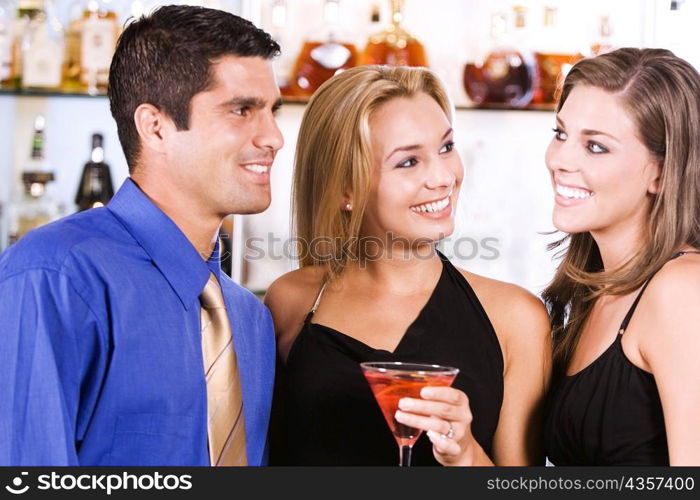 Close-up of two young women and a mid adult man in a bar