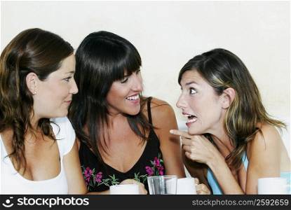 Close-up of two young women and a mid adult woman gossiping