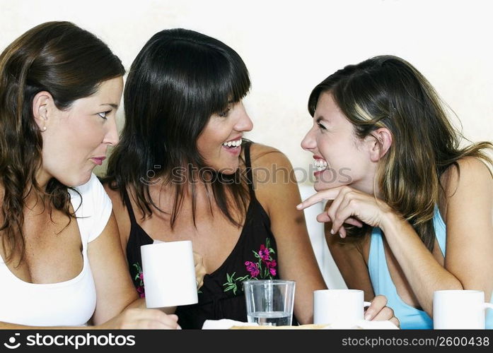 Close-up of two young women and a mid adult woman gossiping