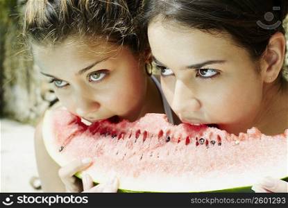 Close-up of two young women eating a slice of watermelon