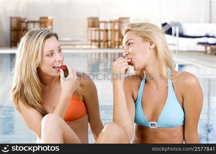 Close-up of two young women eating strawberries